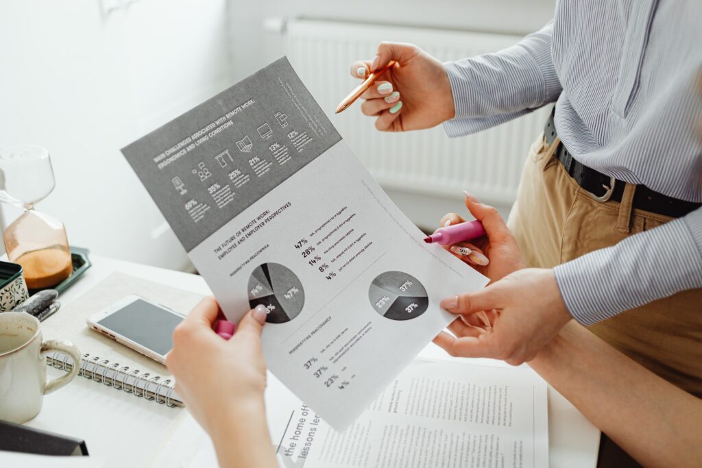 Two people looking at black and white financial report with numbers and pie graphs