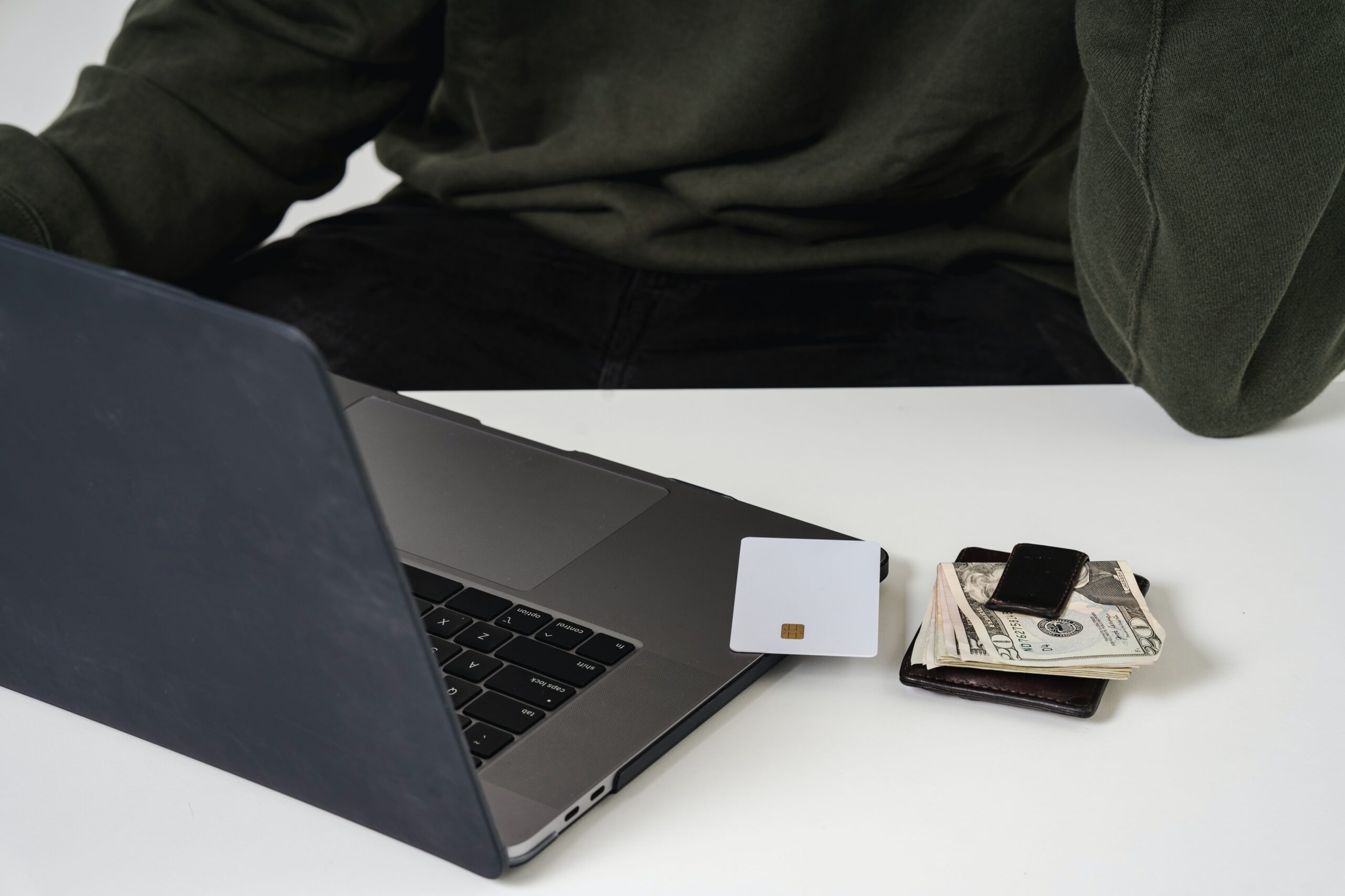 a black laptop with cash and credit cards on top talking about cybersecurity for shares